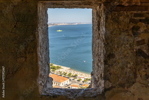 Looking out through a granite window over the ocean and beach from a mountaintop fortress in Setubal.