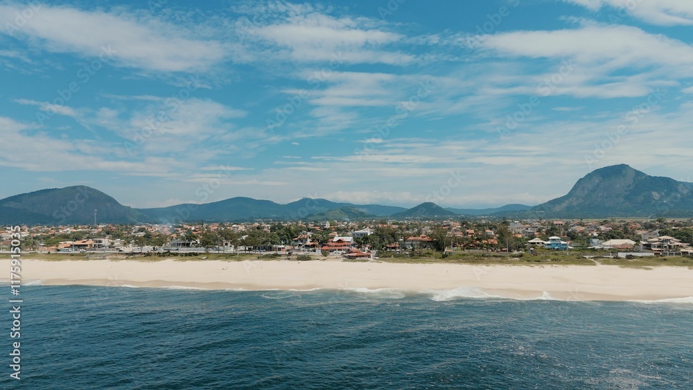 Obraz premium Coastal town with beach and mountains.