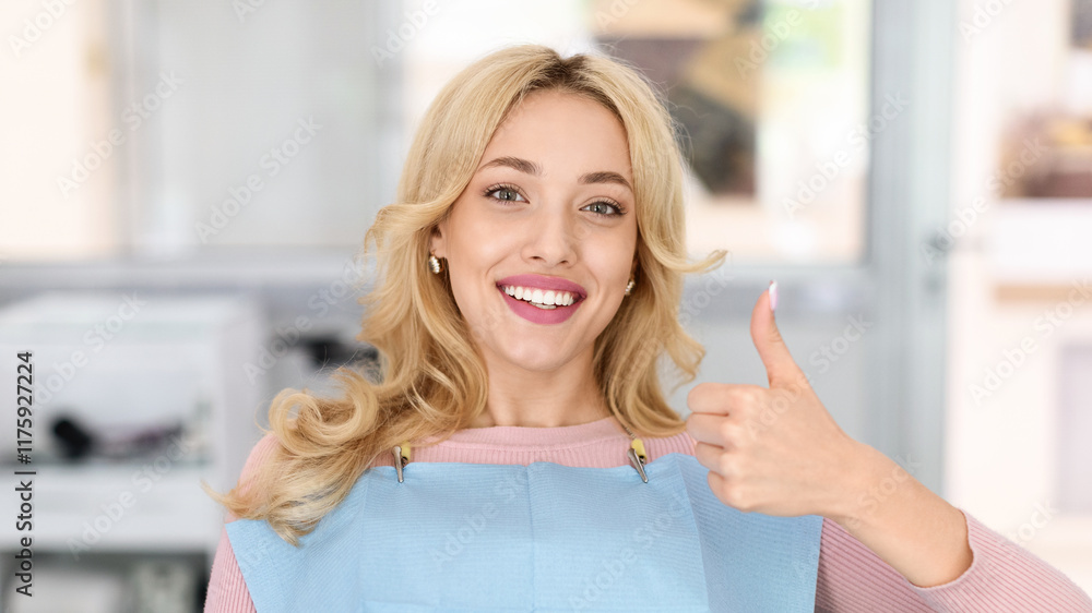 Fototapeta premium Pretty blonde lady showing her beautiful healthy smile and thumb up, panorama with copy space. Female patient of modern dental clinic sitting in chair, recommending her dentist, closeup