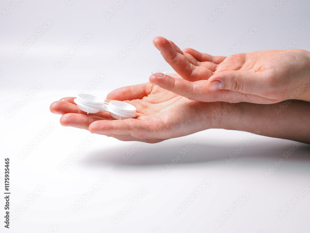 Hands holding a contact lens and an open lens case on a white background. Concept of eye care, hygiene, and vision correction Hands holding a contact lens and an open lens case on a white background. Concept of eye care, hygiene, and vision correction