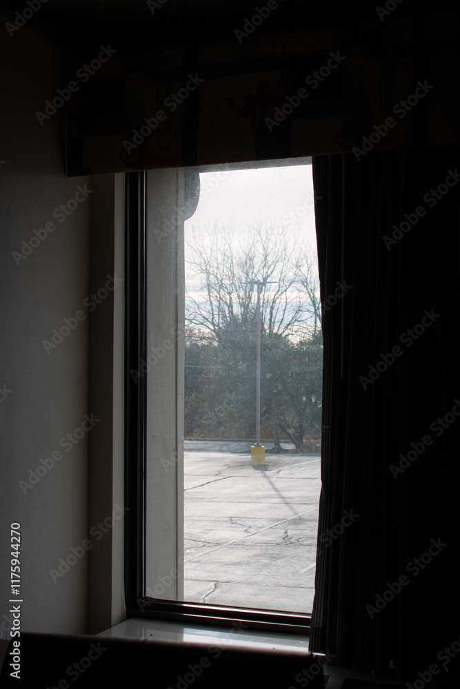 Blick aus einem Fenster auf einen leeren Parkplatz und kahle Bäume Blick aus einem Fenster auf einen leeren Parkplatz und kahle Bäume