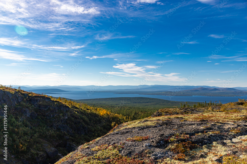 Aerial view of autumn taiga forest and Imandra lake at foreground. Khibiny mountains with blue sky and small clouds. Northern landscape at Kola Peninsula, Russia