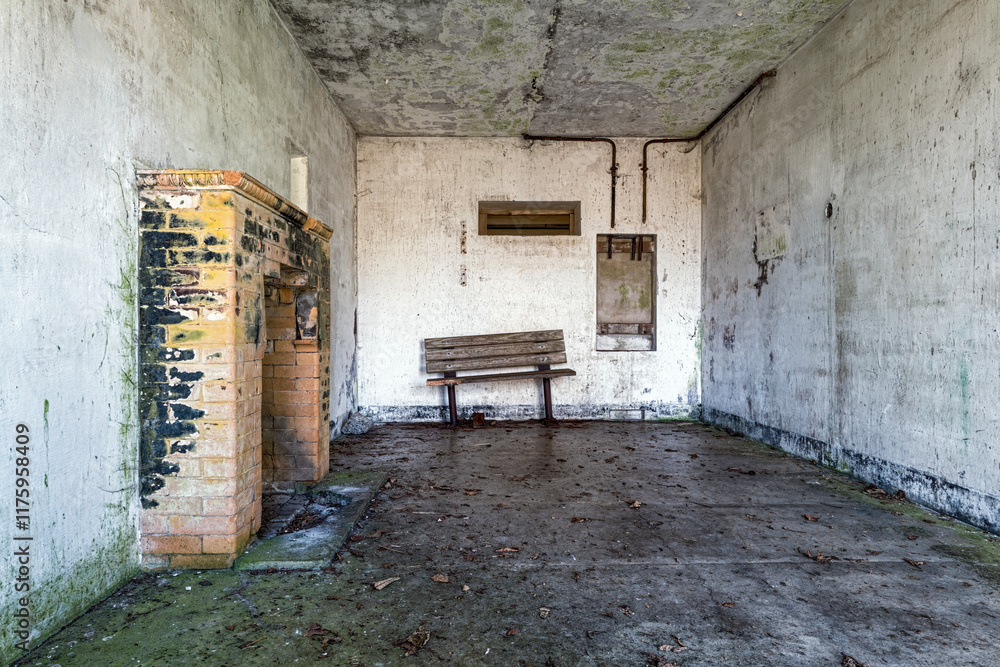 A brick fireplace and a broken bench along the concrete walls of an abandoned WWII military bunker A brick fireplace and a broken bench along the concrete walls of an abandoned WWII military bunker