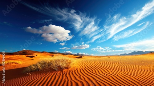 Desert dunes extend magnificently under a vivid blue sky with clouds drifting peacefully photo