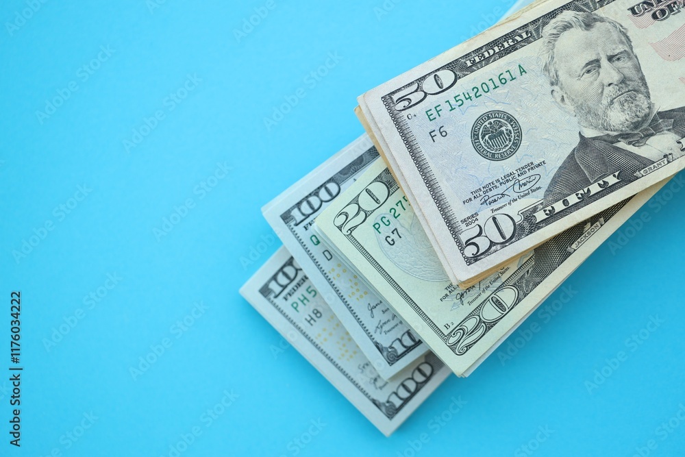 Big amount of hundred, fifty and twenty dollar bills in thick stack lies on bright blue color paper background Big amount of hundred, fifty and twenty dollar bills in thick stack lies on bright blue color paper background