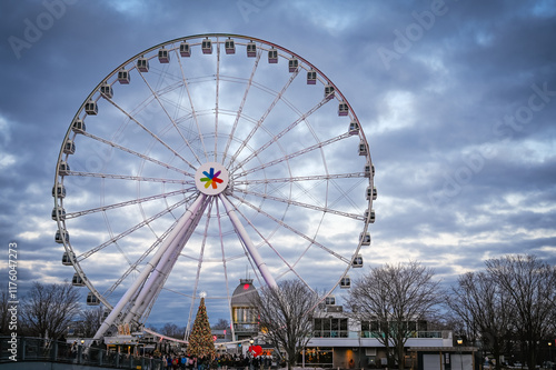 Stunning view of La Grande Roue ferris wheel with beautifully decorated Christmas tree, festive scene is set against a dramatic evening sky at dusk, Old Port, Montreal, Quebec, Canada (December 2024) photo