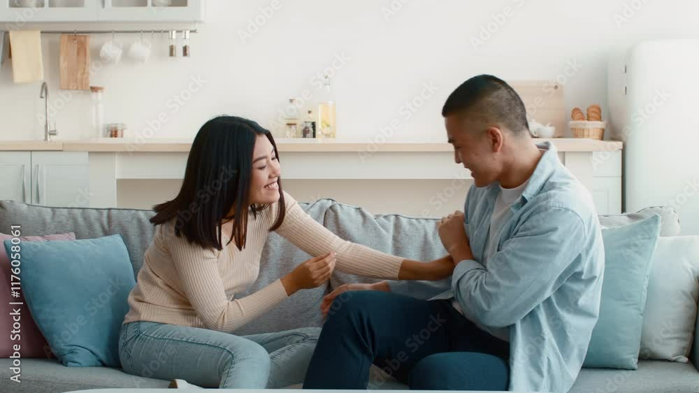 A young couple enjoys a lighthearted moment on a couch in their cozy living room. They are playfully teasing each other, laughing, and sharing a joyful atmosphere in the afternoon sun. A young couple enjoys a lighthearted moment on a couch in their cozy living room. They are playfully teasing each other, laughing, and sharing a joyful atmosphere in the afternoon sun.