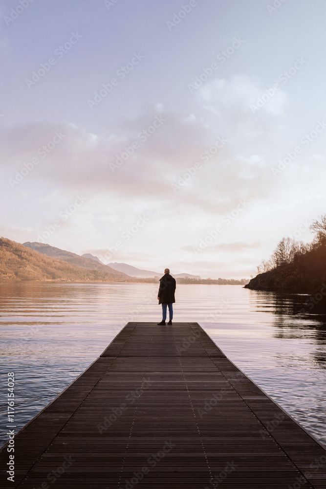 Young man enjoying the calm waters of Lake Mergozzo surrounded by alpine scenery. Young man enjoying the calm waters of Lake Mergozzo surrounded by alpine scenery.