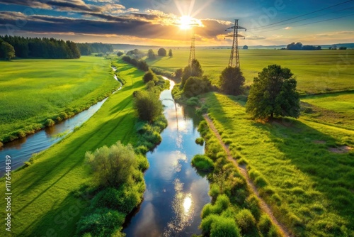 Grassy field, tranquil stream, and overhead power lines captured in a breathtaking drone aerial view.