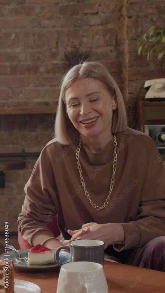 Vertical of mid-adult Caucasian woman speaking to someone while sitting against each other at table in stylish cafe with modern design, with exposed red brick walls Vertical of mid-adult Caucasian woman speaking to someone while sitting against each other at table in stylish cafe with modern design, with exposed red brick walls