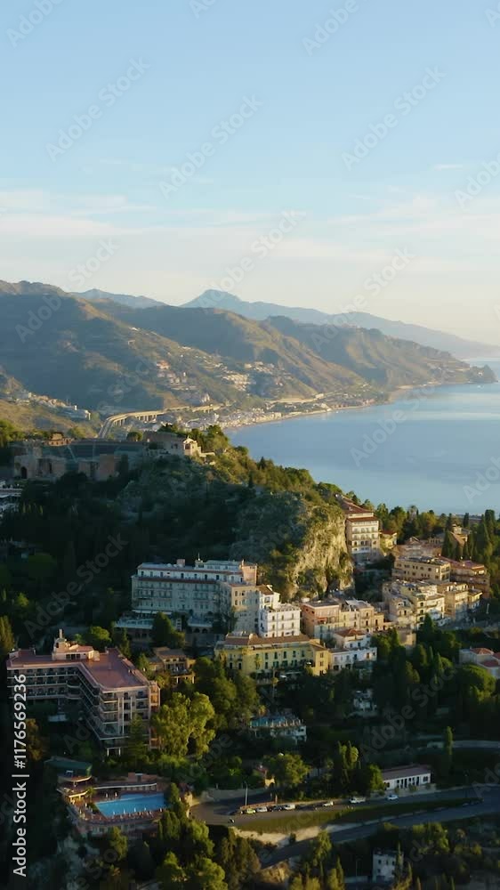 Ancient theater on top of a rocky mountain in Taormina. Aerial orbit drone shot over the historic town of Taormina. Nature landscape in Sicily. Vertical video. Ancient theater on top of a rocky mountain in Taormina. Aerial orbit drone shot over the historic town of Taormina. Nature landscape in Sicily. Vertical video.