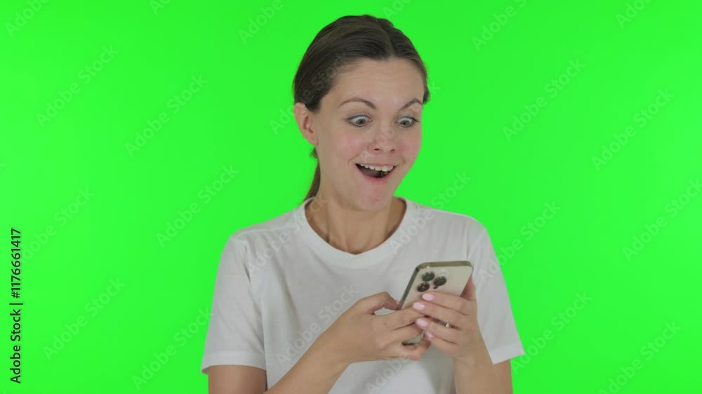 Young Woman Celebrating Success on Phone on Green Background Young Woman Celebrating Success on Phone on Green Background