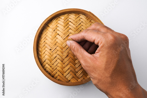 Close-up photo of Someone hand is opening wooden dimsum steamer container isolated on white background. Shot on 30 Degree, flat lay angle setup photo