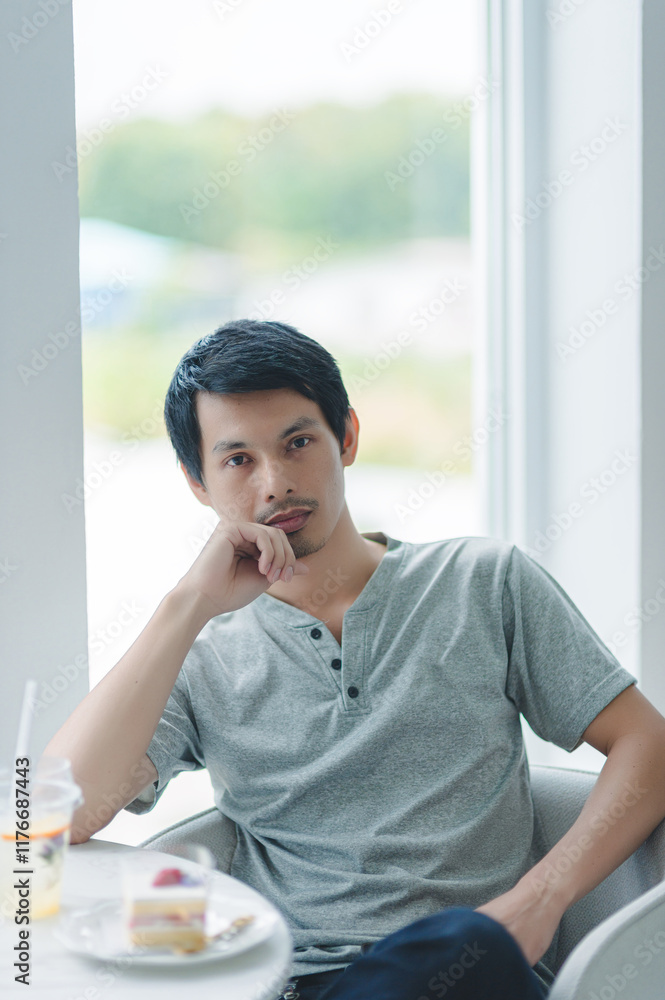 Thoughtful young man sitting by the window in a modern café Thoughtful young man sitting by the window in a modern café