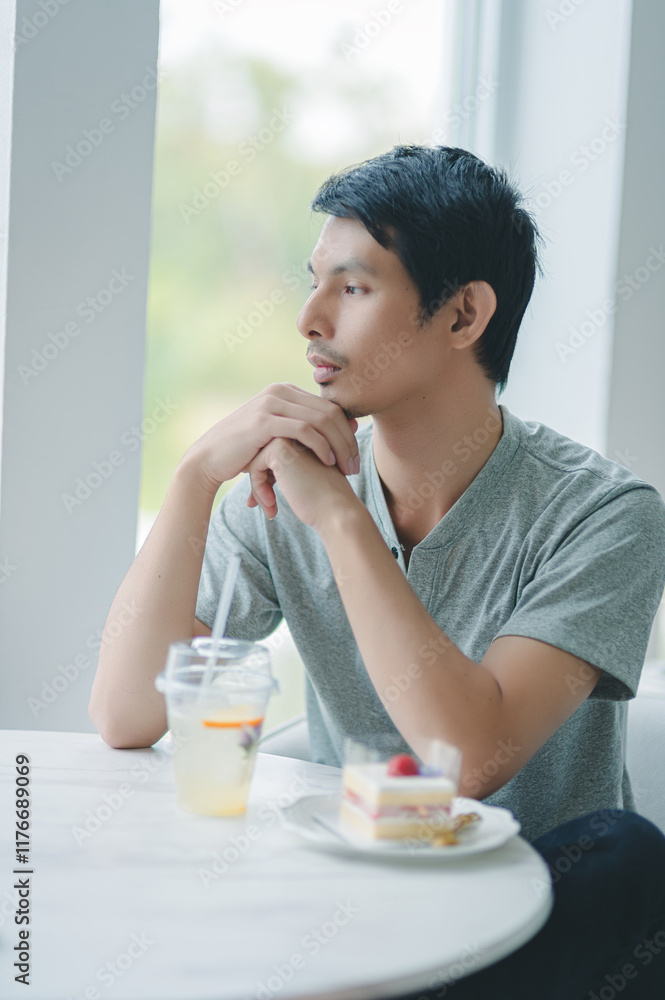 Thoughtful Young Man in Casual Attire Enjoying Dessert and Drink Thoughtful Young Man in Casual Attire Enjoying Dessert and Drink
