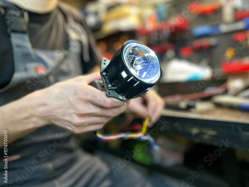 Installation of BI-LED lenses in the headlight. Restoration of car optics. A man holds a bi-led lens in his hands. Car headlight in repair close-up. Car tuning and styling.  photo