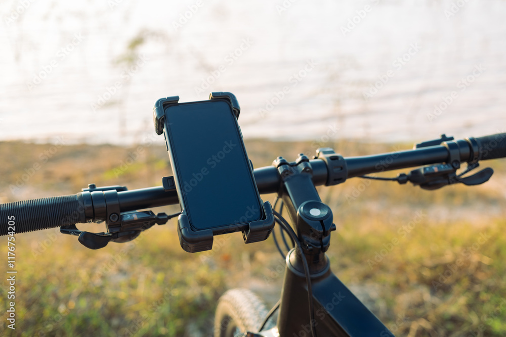 Closeup smartphone and holder attached to the handlebar of a bicycle while parking at the lake in the nature Closeup smartphone and holder attached to the handlebar of a bicycle while parking at the lake in the nature