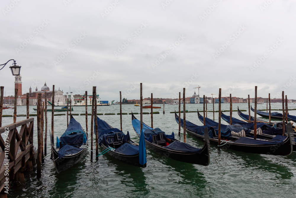 Gondolas moored on the water in Venice, Italy, with the cityscape and the Campanile di San Giorgio Maggiore in the background Gondolas moored on the water in Venice, Italy, with the cityscape and the Campanile di San Giorgio Maggiore in the background