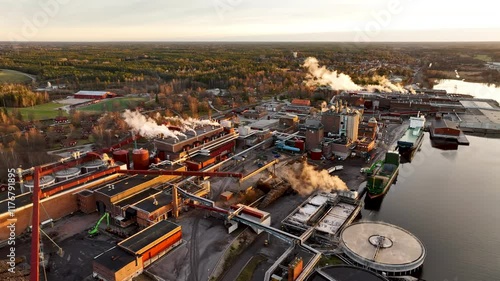 Pulp and paper mill releasing steam and smoke at sunset