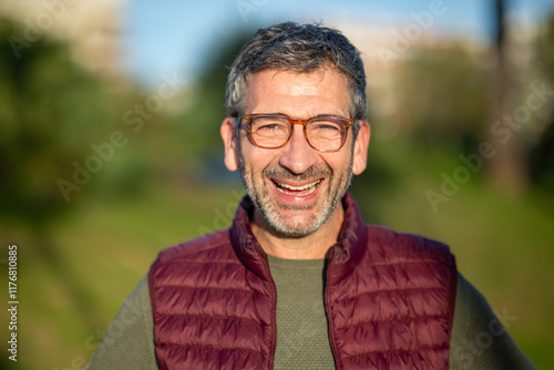 Laughing man wearing glasses outdoors in sunny park