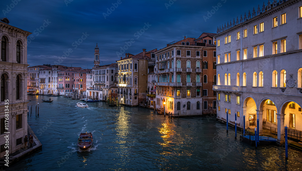 Fototapeta premium Grand Canal of Venice illuminated at dusk showcasing stunning architecture and serene boat travel seen from the Rialto Bridge