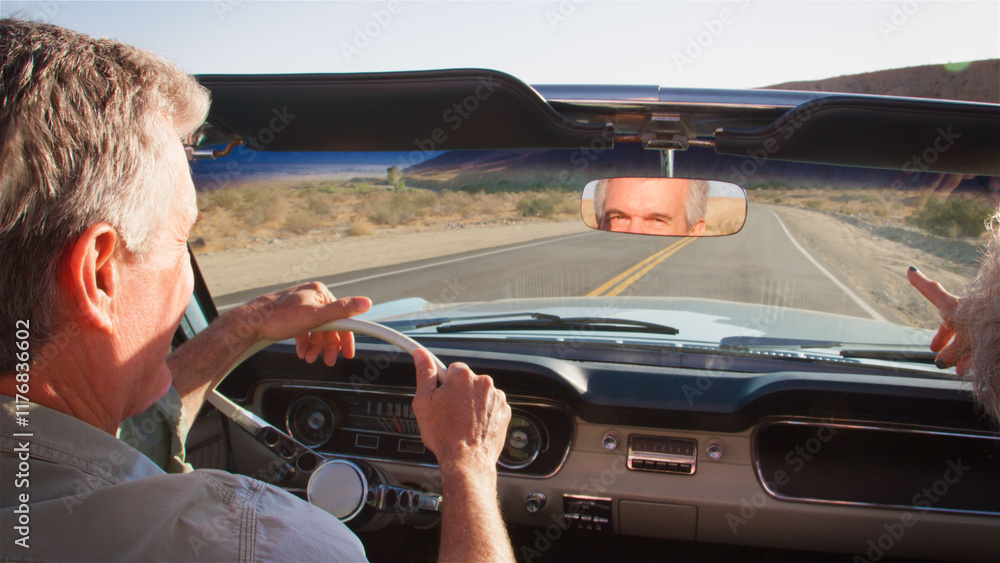 Naklejka premium Rear View Of Senior Couple On Road Trip Driving In Classic Convertible Car Along Country Road