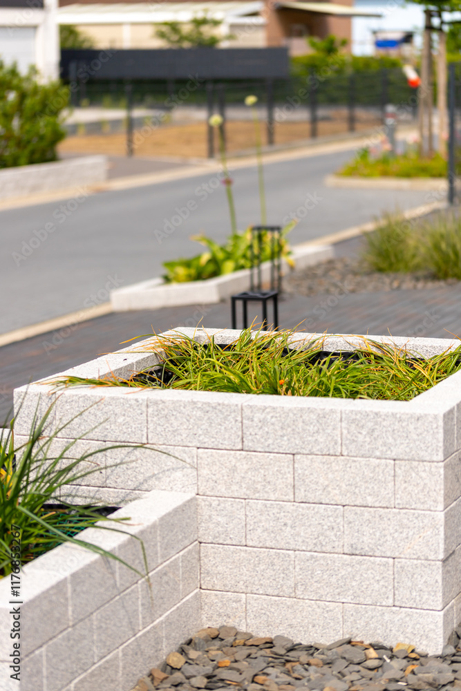 Obraz premium Raised bed made of natural stone bricks with grass as content, street in the background