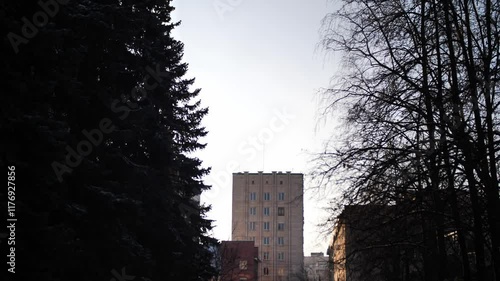 Soviet-style apartment building emerging through winter fog and trees, ideal for urban documentaries, architectural presentations, historical projects, city planning materials and modern slow motion