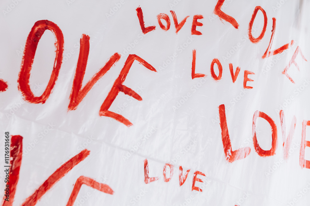 Multiple drawings of the word LOVE hand-painted in bright red forming a pattern on a plain white surface oilcloth, Valentine`s day concept celebration decoration in photo studio. Love, holiday, party Multiple drawings of the word LOVE hand-painted in bright red forming a pattern on a plain white surface oilcloth, Valentine`s day concept celebration decoration in photo studio. Love, holiday, party