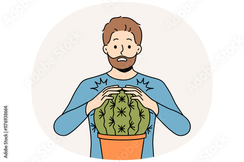 Man is scared and touches cactus and gets wound for concept of problems associated with unshaven hair and need for depilation. Funny stupid guy pricked himself touching cactus in pot