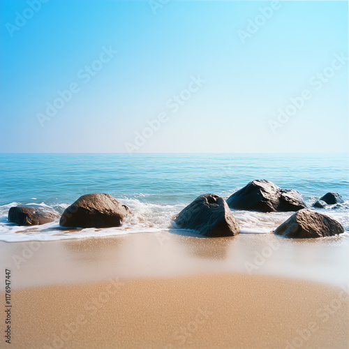 Serene ocean view with smooth rocks on a sandy beach, under a clear blue sky, showcasing the beauty of nature. photo