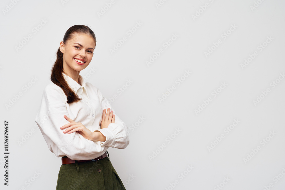 Smiling businesswoman in a white shirt standing with arms crossed against a light grey background, showcasing confidence and professionalism, appealing for corporate imagery Smiling businesswoman in a white shirt standing with arms crossed against a light grey background, showcasing confidence and professionalism, appealing for corporate imagery