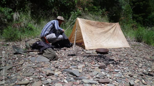 Australian bushman sets up a traditional oldschool camp on a river bank. photo