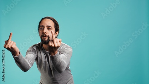 Irked man fighting with friend, doing middle finger sign gesturing, isolated over studio background. Outraged person arguing during conversation, doing obscene hand gestures, camera B