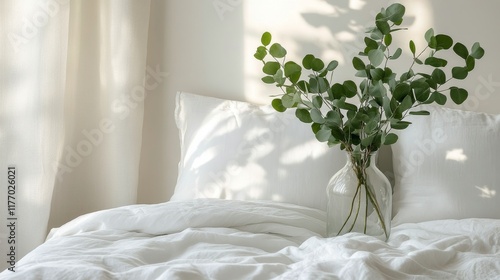Cozy bedroom interior featuring a vase with greenery on a soft white bed duri...