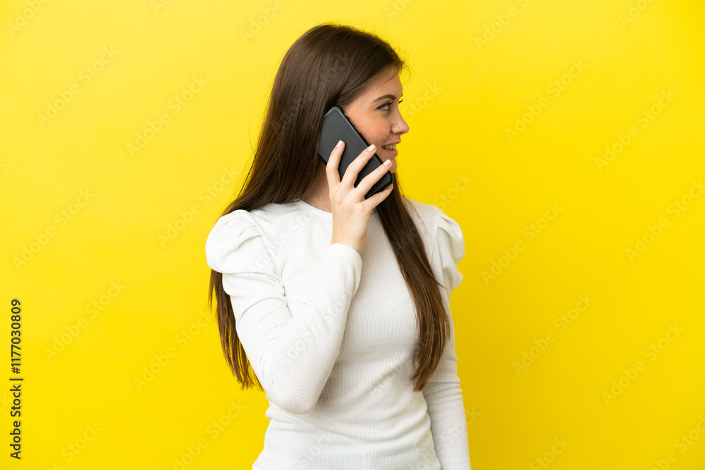 Young caucasian woman isolated on yellow background keeping a conversation with the mobile phone with someone Young caucasian woman isolated on yellow background keeping a conversation with the mobile phone with someone
