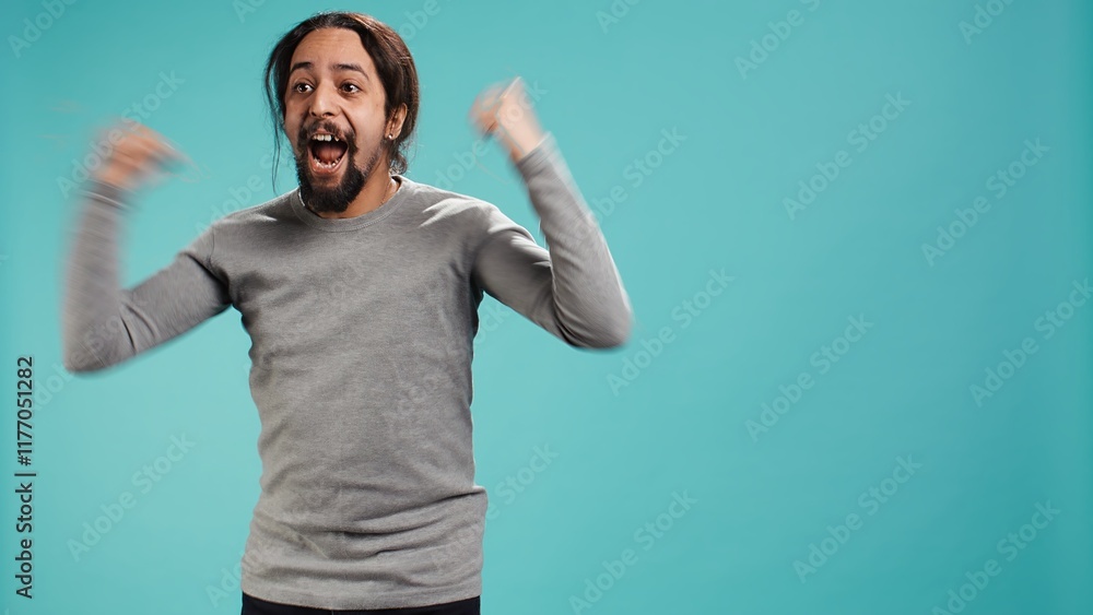 Man jumping from joy in excitement while cheering for favorite sports team, studio background. Person celebrating after victory, showing intense enthusiasm, supporting team during game, camera B Man jumping from joy in excitement while cheering for favorite sports team, studio background. Person celebrating after victory, showing intense enthusiasm, supporting team during game, camera B