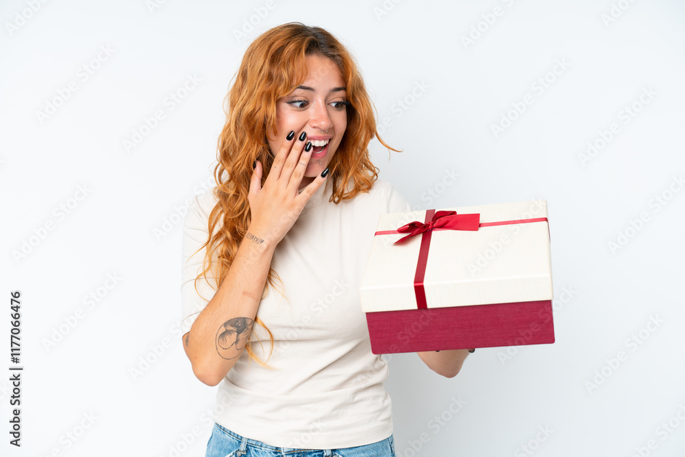 Young caucasian woman holding a gift iso0lated on white background with surprise and shocked facial expression Young caucasian woman holding a gift iso0lated on white background with surprise and shocked facial expression