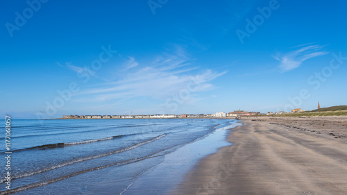 Looking over the waters of Troon Bay Bay in Scotland with blue Skys and gentle waters lapping the beach.