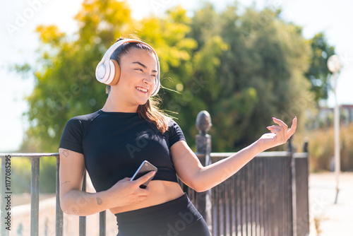 Young pretty brunette woman listening music and doing guitar gesture photo