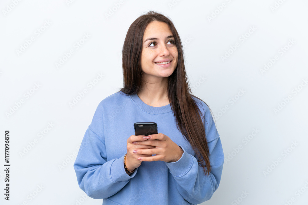 Young Ukrainian woman isolated on white background using mobile phone and looking up Young Ukrainian woman isolated on white background using mobile phone and looking up