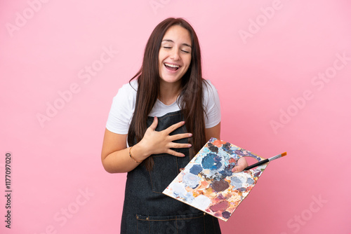 Young artist Ukrainian woman holding a palette isolated on oink background smiling a lot photo