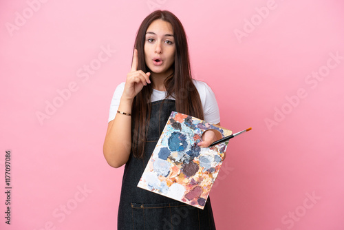 Young artist Ukrainian woman holding a palette isolated on oink background intending to realizes the solution while lifting a finger up photo