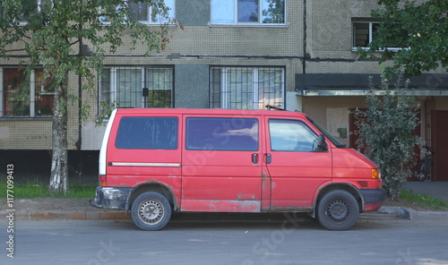 An old rusty red minibus is parked in the courtyard of an apartment building, Podvoysky Street, St. Petersburg, Russia, July 25, 2024
