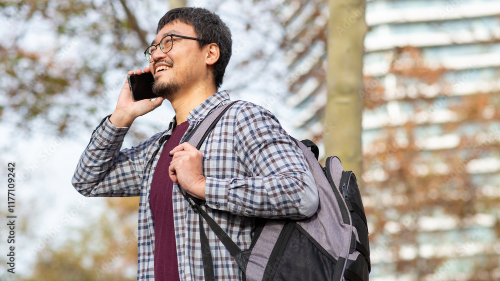 Smiling Asian man talking on phone in outdoor urban park Smiling Asian man talking on phone in outdoor urban park