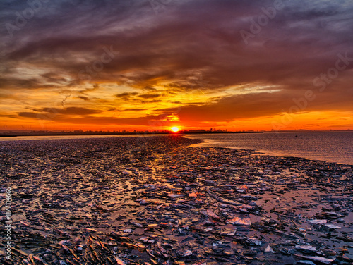 Dawn at the Frozen Lake
Eine atemberaubende Landschaft, bei der die aufgehende Sonne den Himmel in lebhaften Orange- und Blautönen färbt, während zerbrochenes Eis die Oberfläche eines gefrorenen Sees  photo