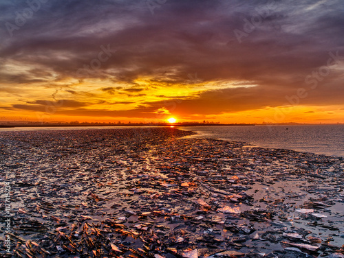 Dawn at the Frozen Lake
Eine atemberaubende Landschaft, bei der die aufgehende Sonne den Himmel in lebhaften Orange- und Blautönen färbt, während zerbrochenes Eis die Oberfläche eines gefrorenen Sees  photo