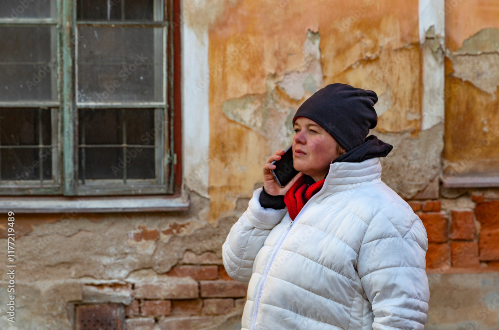 A plus-size woman walking through the streets of a small town and talking on the phone.