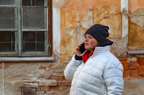 A plus-size woman walking through the streets of a small town and talking on the phone.