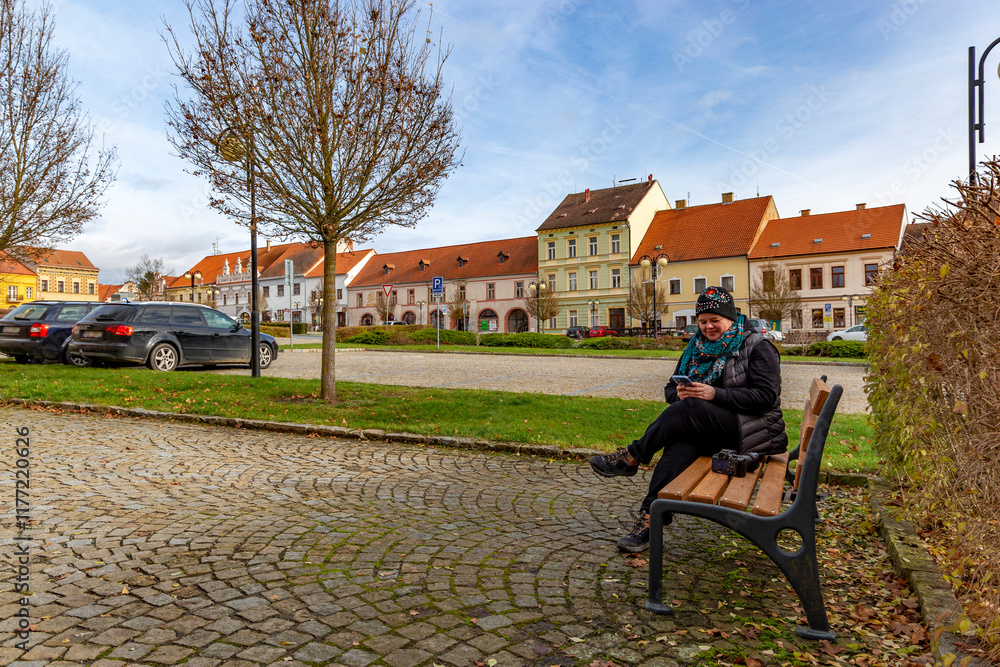 A woman with a camera sitting on a bench in an autumn city.